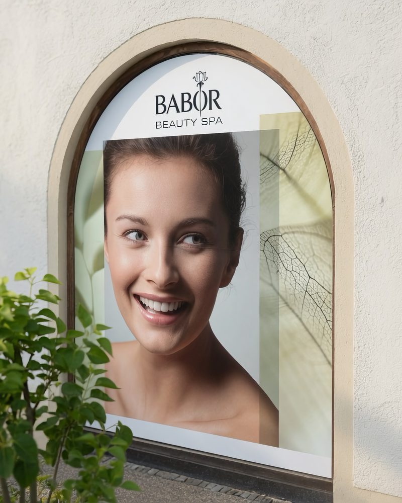 Schaufensterverklebung mit BABOR-Motiv in einem bogenförmigen Fenster