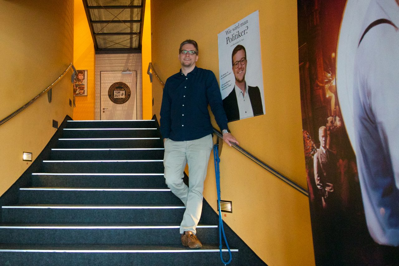 Maximilian Auer bei der Kinopremiere seines Dokumentarfilms neben dem Filmplakat