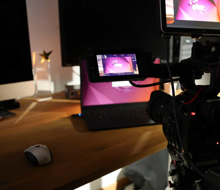 Eine große Filmkamera mit zwei Monitoren filmt einen Laptop